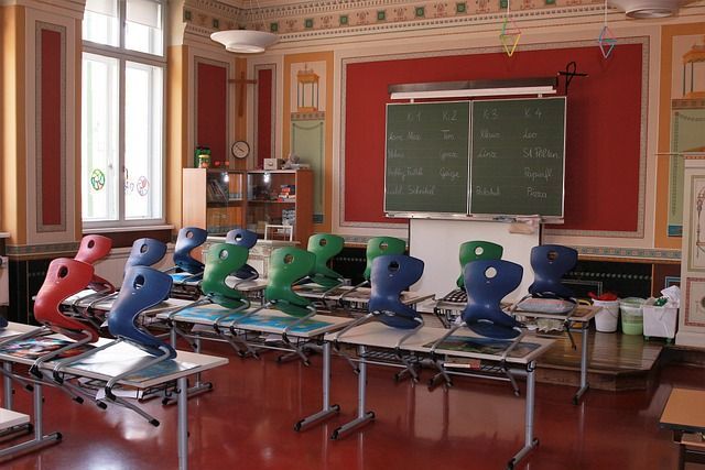 Klassenzimmer mit hochgestellten Stühlen und Blick auf die Tafel